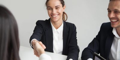 Smiling female hr handshaking employee welcoming hired worker, new team member, cheerful positive businesswoman shaking hand of partner satisfied with deal, making good first impression concept